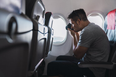 Mann beim Fotografieren im Flugzeug - KKAF02465