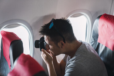 Mann beim Fotografieren im Flugzeug - KKAF02466