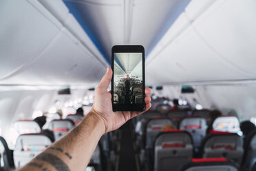 Flugzeug, Mann, der ein Smartphone benutzt und ein Foto im Inneren macht - KKAF02467