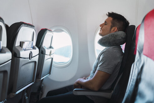 Man sleeping with neck pillow in airplane - KKAF02468