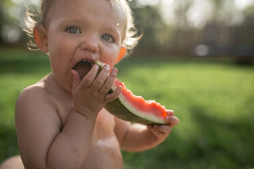 Nahaufnahme eines hemdsärmeligen kleinen Mädchens, das im Garten eine Wassermelone isst - CAVF50121