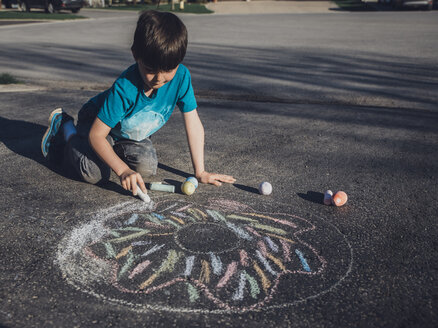 Junge zeichnet mit Kreide auf Asphalt - CAVF50124