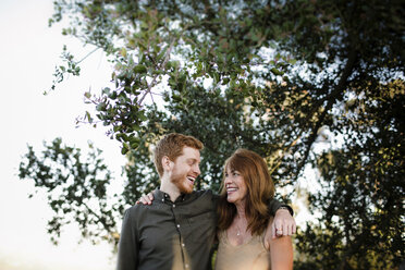 Low angle view of happy mother and son looking at each other while standing against trees at park - CAVF50146