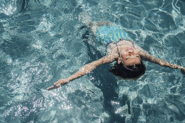 High angle view of girl with arms outstretched swimming in pool during sunny day - CAVF50195