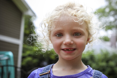 Close-up-Porträt von niedlichen Mädchen mit unordentlichen blonden Haaren stehen gegen den Himmel im Hof, lizenzfreies Stockfoto