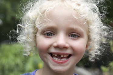 Close-up portrait of happy girl with messy blond hair standing at yard - CAVF50204