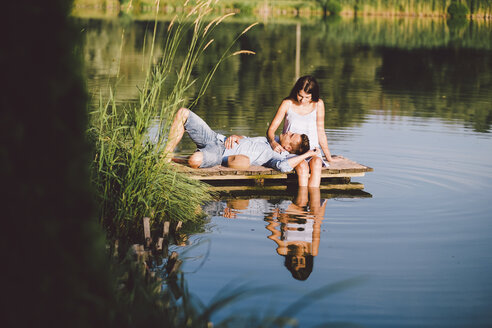 Boyfriend lying on girlfriend's lap by lake at park - CAVF50242