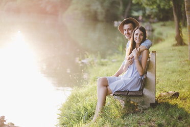 Porträt eines Paares, das auf einer Bank am See im Park sitzt - CAVF50248