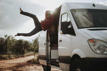 Glücklicher Mann hängt an einem Wohnmobil gegen den Himmel im Wald - CAVF50254