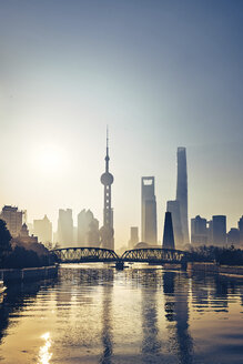 Silhouette bridge over Huangpu River against modern skyscrapers during sunset - CAVF50270