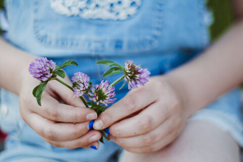 Midsection of girl holding flowers while sitting outdoors stock photo