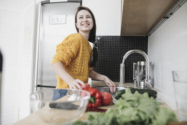 Portrait of happy young woman preparing salad in modern kitchen - KMKF00573