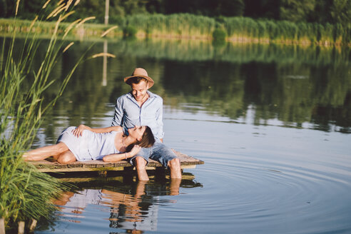 Girlfriend lying on boyfriend's lap by lake at park - CAVF50313