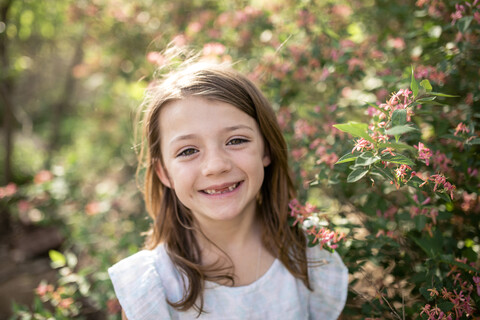 Nahaufnahme eines glücklichen Mädchens, das bei Pflanzen im Park steht, lizenzfreies Stockfoto