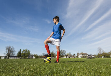 Niedriger Blickwinkel auf einen Jungen mit Fußball auf einer Wiese - CAVF50331