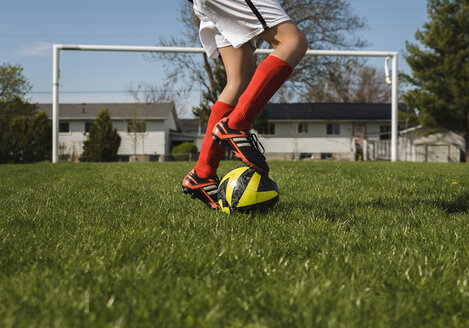 Low section of boy playing with soccer ball on grassy field - CAVF50332