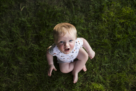 Hohe Winkel Porträt der niedlichen Baby Junge sitzt auf grasbewachsenen Feld im Park, lizenzfreies Stockfoto