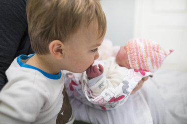 Niedlicher Bruder küsst die Hand der neugeborenen Schwester, die von der Mutter zu Hause getragen wird - CAVF50373