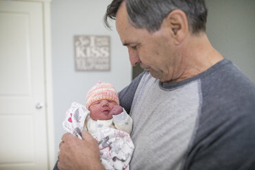 Großvater trägt neugeborene Enkelin im Stehen nach Hause - CAVF50374