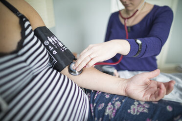 Midsection of midwife examining pregnant woman at home - CAVF50377