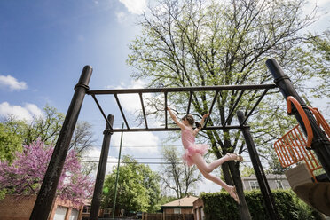 Niedriger Blickwinkel von Mädchen in Ballettkostüm hängen auf Affe Bars gegen Himmel auf dem Spielplatz - CAVF50390