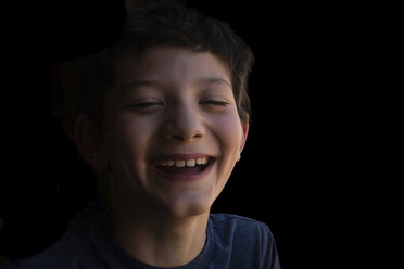 Close-up-Porträt von glücklichen Jungen lachend gegen schwarzen Hintergrund - CAVF50441