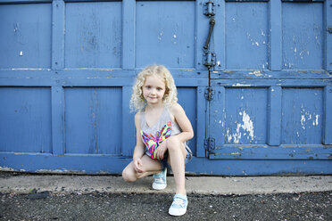 Portrait of girl crouching by blue door - CAVF50442