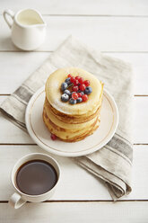 Hohe Winkelansicht von Pfannkuchen in Platte mit Kaffee und Milch auf Holztisch serviert - CAVF50461