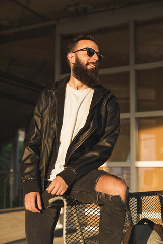 Stilvoller bärtiger junger Mann im Freien mit Blick zur Seite, lizenzfreies Stockfoto