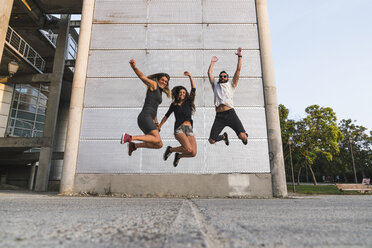 Exuberant friends jumping outdoors - KKAF02499