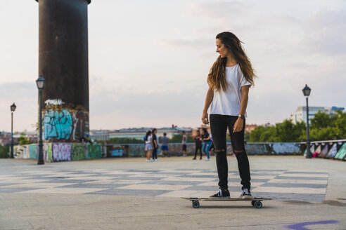 Junge Frau fährt Skateboard in der Stadt - KKAF02517