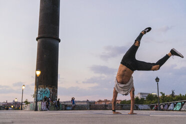 Young man doing a catwheel in the city at sunset - KKAF02529