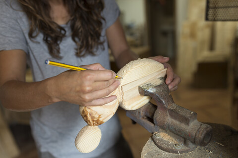 Craftswoman working with pencil on a piece of wood in her workshop stock photo