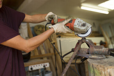 Handwerkerin mit Winkelschleifer in ihrer Werkstatt - JPTF00043