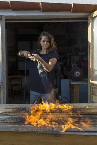 Handwerkerin brennt Holz in ihrer Werkstatt, lizenzfreies Stockfoto