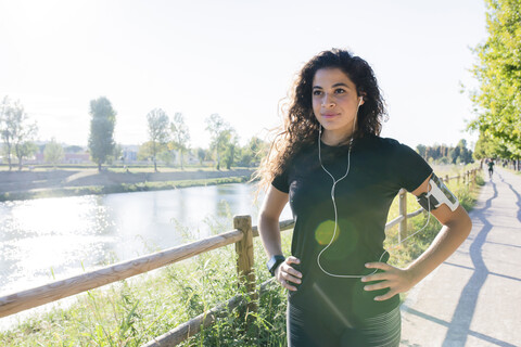 Sportliche junge Frau, die eine Pause am Flussufer einlegt, lizenzfreies Stockfoto