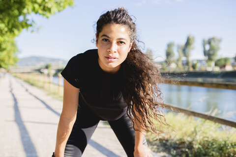 Portrait of sportive young woman having a break at the riverside stock photo