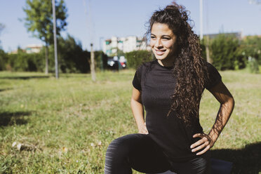 Sportliche junge Frau beim Training auf einer Wiese - FMOF00391