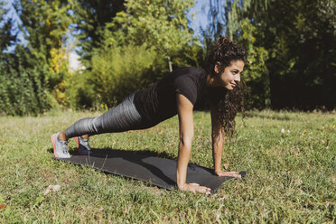 Sporty young woman doing push-ups on a meadow - FMOF00392