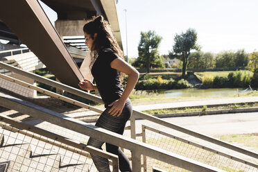 Sportliche junge Frau läuft auf einer Treppe - FMOF00402