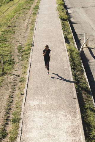 Sportliche junge Frau beim Laufen auf einem Pfad, lizenzfreies Stockfoto