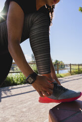 Woman tying her shoe before workout - FMOF00408