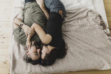 Couple lying on bed, kissing, cuddling and embracing - KMKF00587