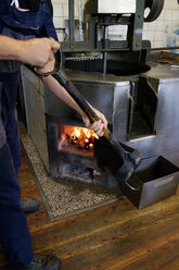 Mann heizt Rührwerkskessel mit Kohle in einer Ölmühle - HLF01130