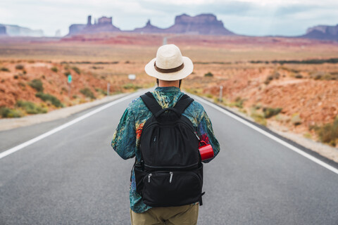 USA, Utah, Mann mit Rucksack auf dem Weg zum Monument Valley, lizenzfreies Stockfoto