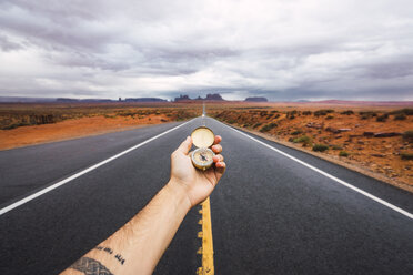 USA, Utah, Hand hält Kompass über Straße nach Monument Valley - KKAF02541