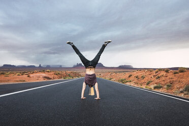 USA, Utah, Junger Mann macht Handstand auf dem Weg zum Monument Valley - KKAF02545