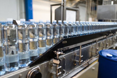 Nahaufnahme von Wasserflaschen in einer Reihe in einer Lebensmittelverarbeitungsanlage in einer Fabrik - CAVF50508