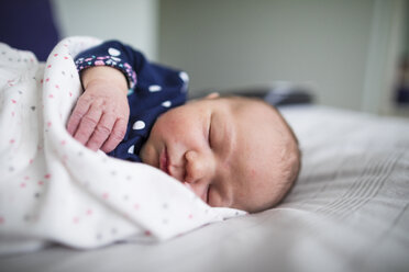 Nahaufnahme eines süßen neugeborenen Mädchens, das zu Hause auf dem Bett schläft - CAVF50516