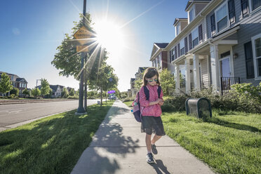 Mädchen mit Rucksack und Sonnenbrille beim Spaziergang auf dem Fußweg gegen den klaren Himmel an einem sonnigen Tag - CAVF50528